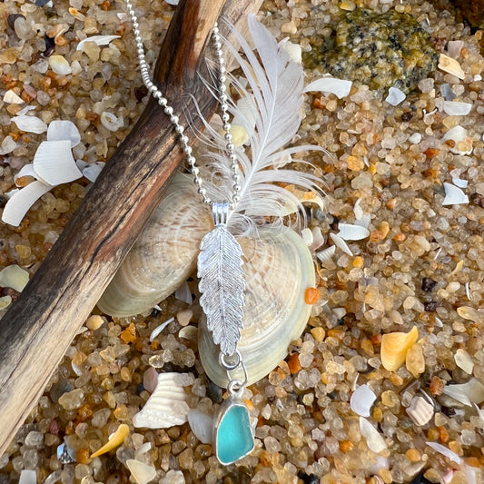 Sterling silver necklace of a cast silver feather with  blue sea glass charm. Hangs on a 40 or 45cm sterling silver chain.  By Mornington Sea Glass