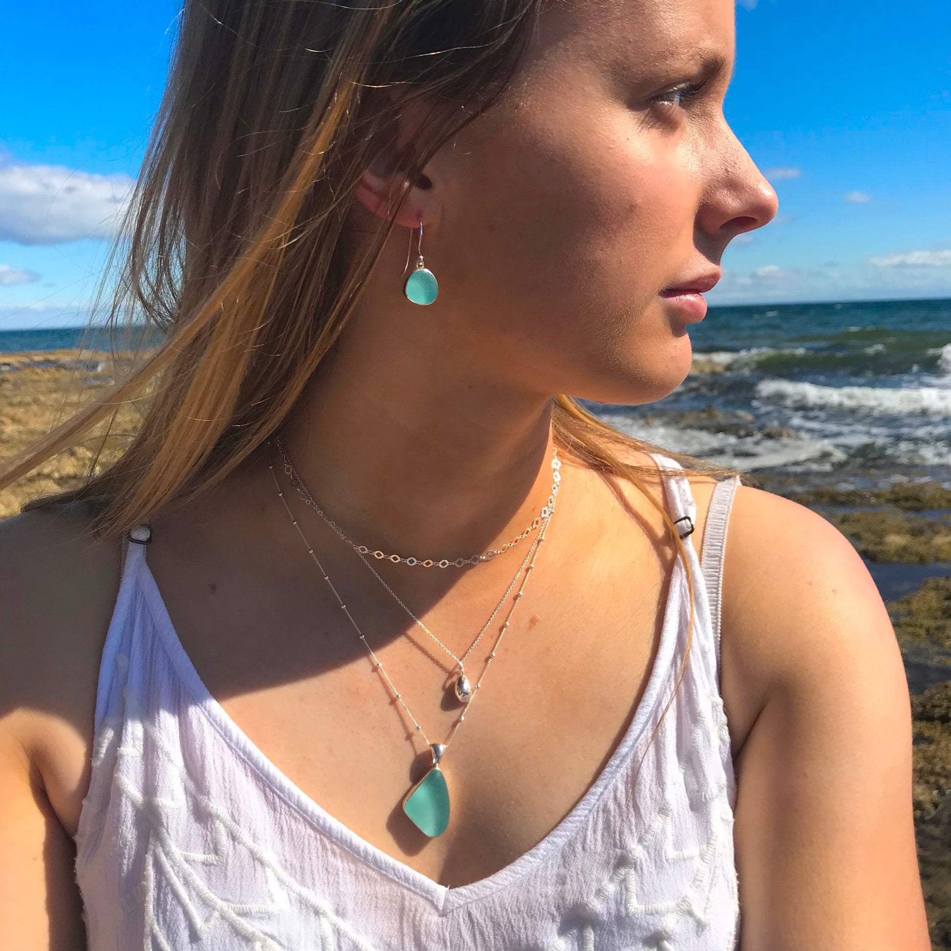 Woman wearing blue sea glass earrings and blue sea glass pendant by Mornington Sea Glass